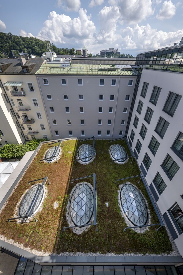 Un edificio de varios pisos con un jardín en la azotea que cuenta con cuatro grandes estructuras de vidrio con forma ovalada.
