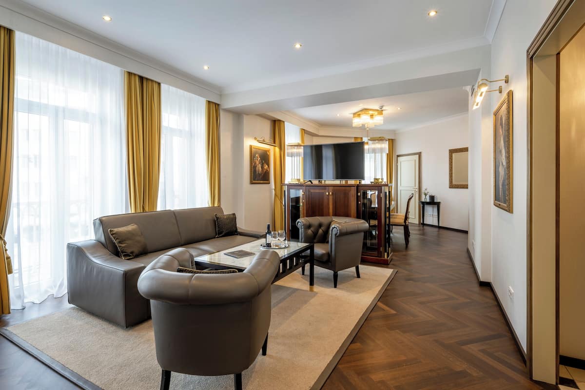 A modern living room with a sofa, armchairs, a coffee table, and a television.