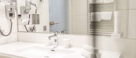 A modern bathroom with a white sink, a hairdryer, and a mirror.