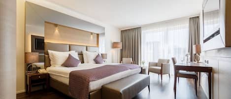 Una habitación de hotel moderna con una cama grande, un escritorio, una silla y un banco.