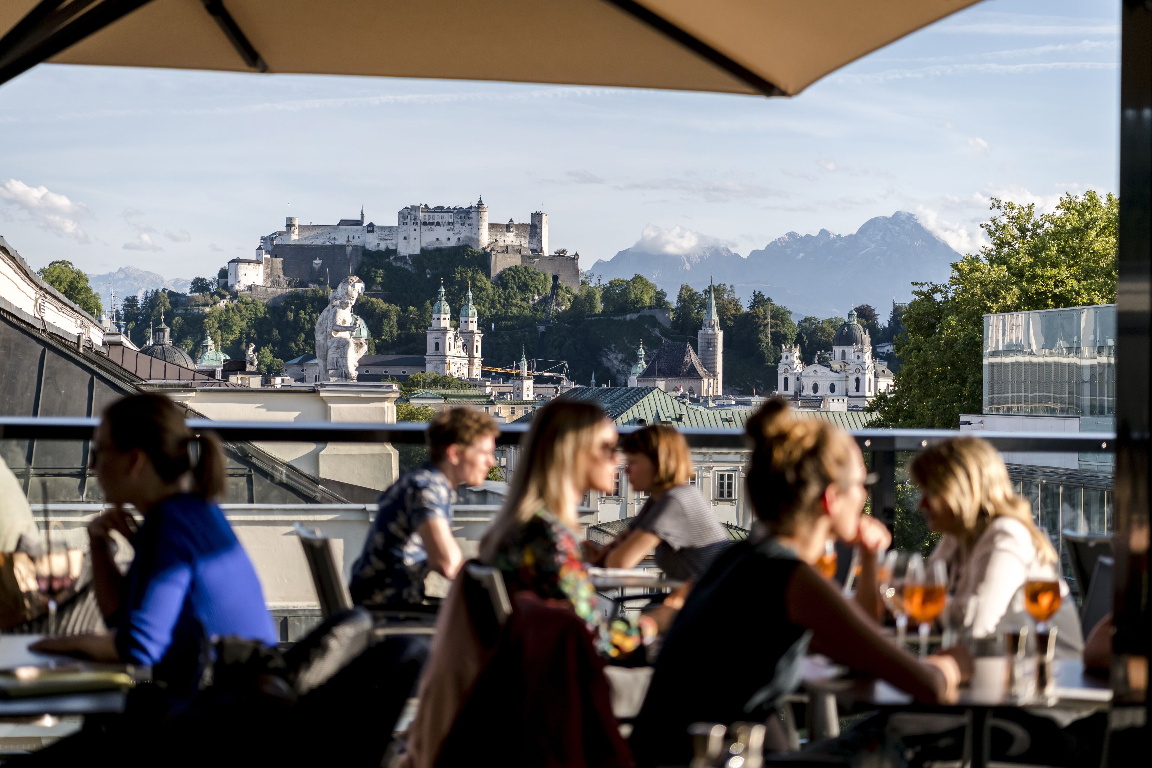 Ein Restaurant mit Außenbereich, das Blick auf eine historische Burg und Berge bietet.