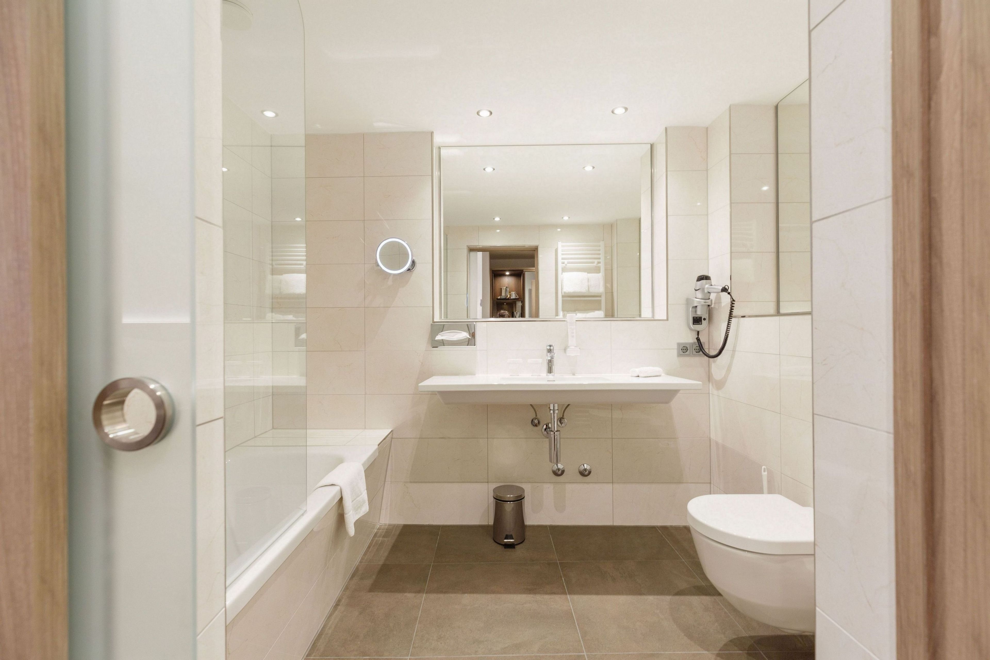 A modern bathroom with a glass shower enclosure, a white sink, a toilet, and a mirror.
