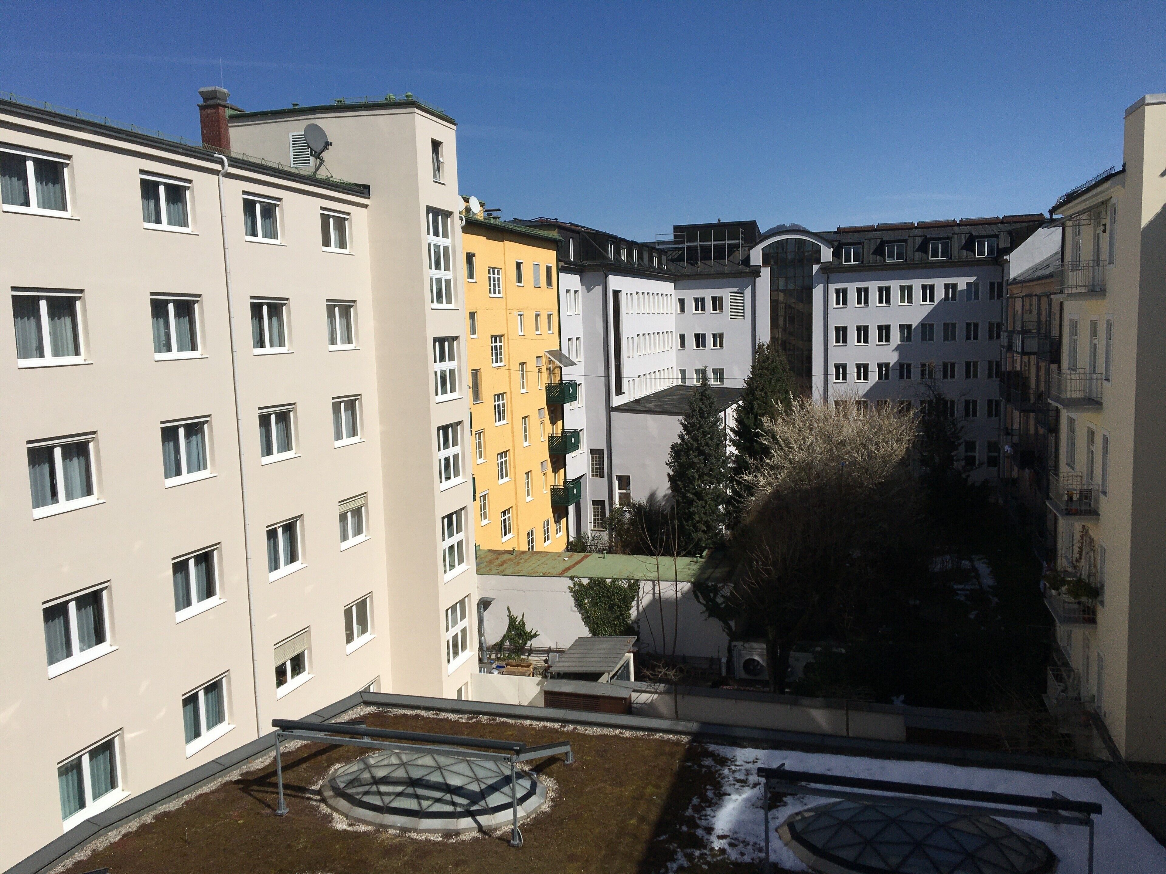 A multi-story residential building with a courtyard featuring a circular water feature and a small garden area.