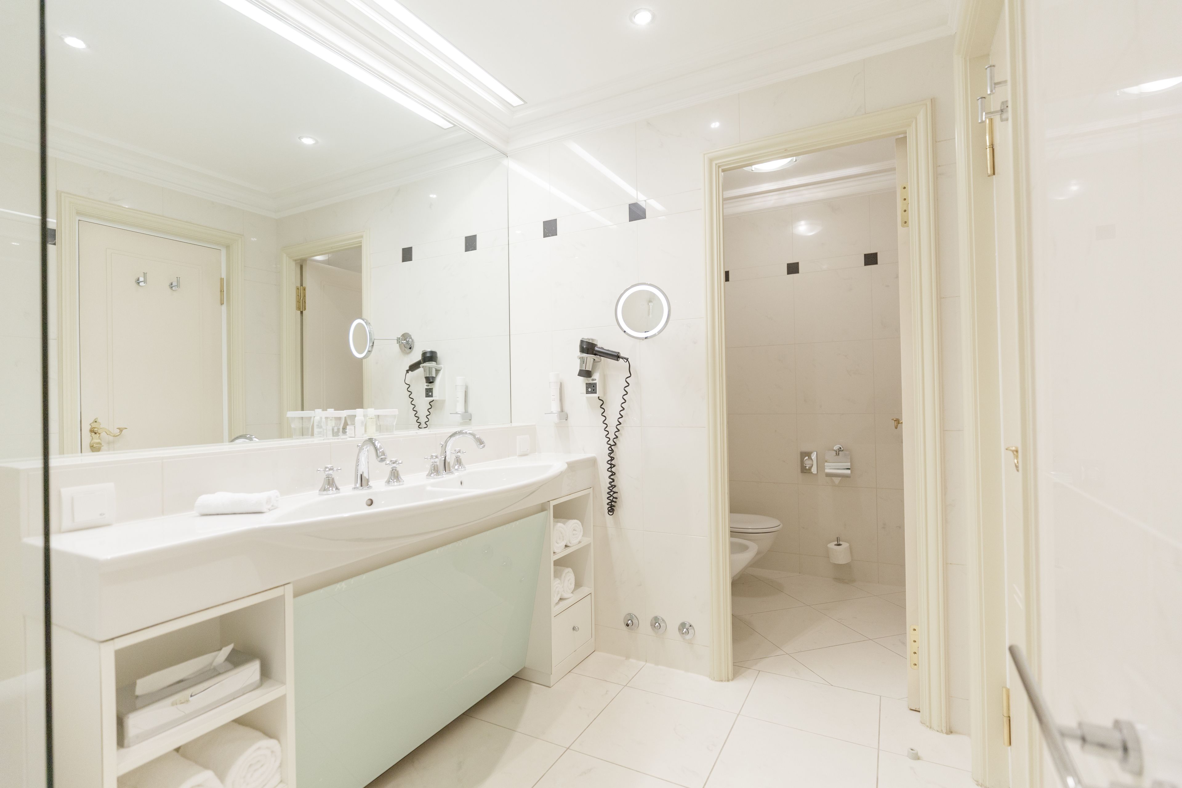 A modern bathroom with a large mirror, a sink, and a shower area.