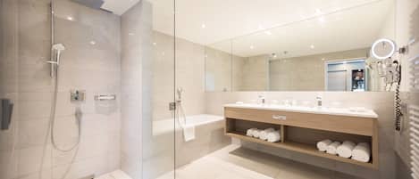Un baño moderno con ducha de vidrio, tocador con espejo y estante empotrado para toallas.
