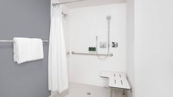 A modern bathroom with a shower, a grab bar, and a small sink.