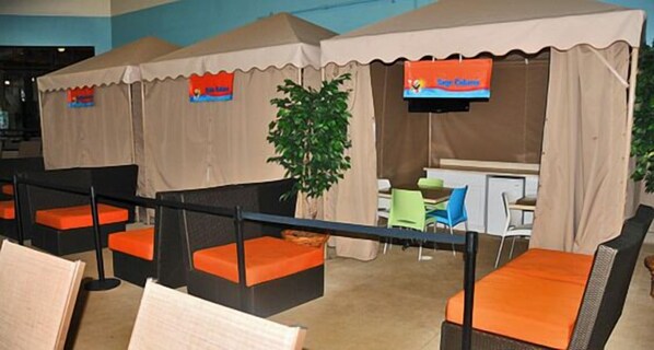 Un espace détente avec des fauteuils confortables et des tables, une petite plante et un panneau au-dessus d’un comptoir.