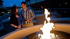 A couple standing near a fire pit with a building in the background. - Soaring Eagle Waterpark and Hotel (Mount Pleasant)