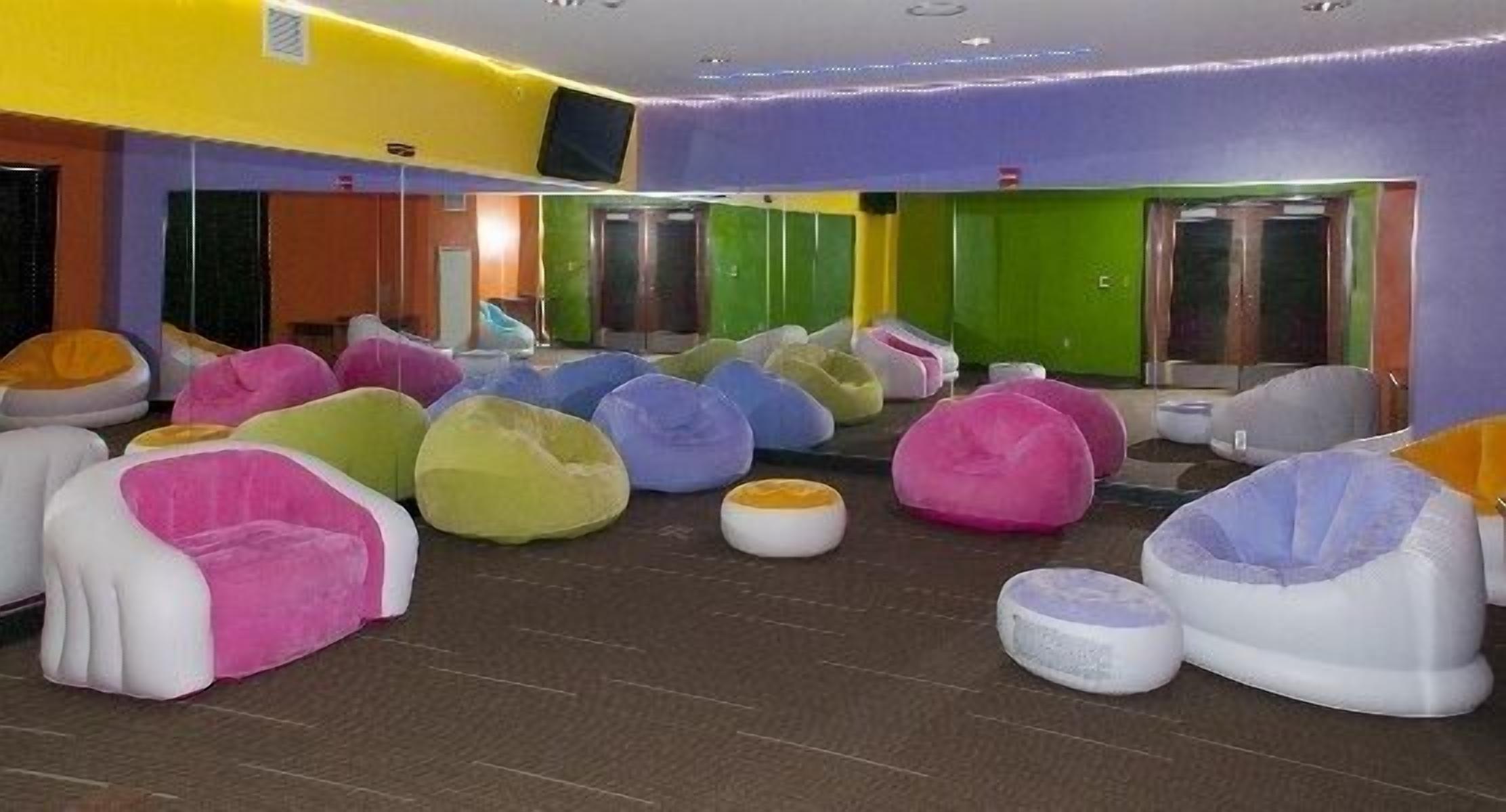A room with colorful bean bags and a green door.