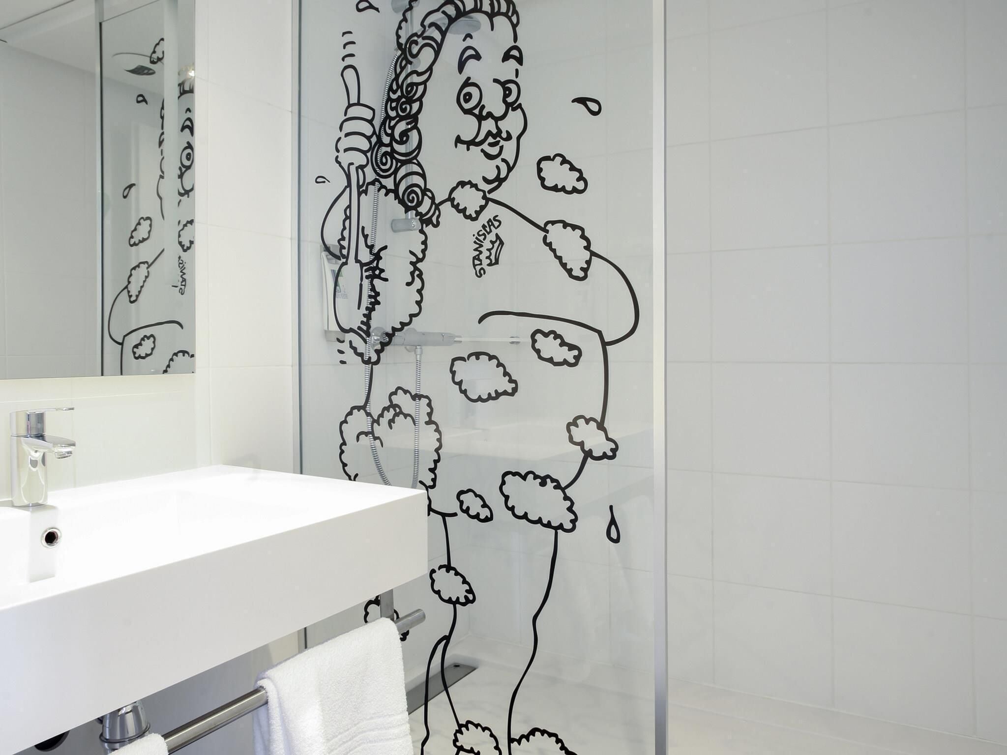 A bathroom with a white sink, a mirror, and a shower curtain with a black floral pattern.