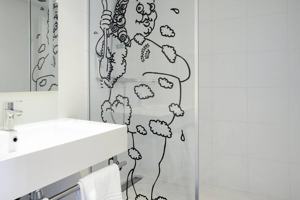 A bathroom with a white sink, a mirror, and a shower curtain with a black floral pattern.