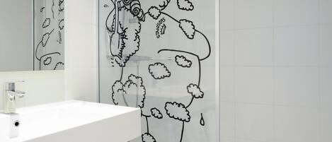 Un baño con lavamanos blanco, espejo y cortina de ducha con estampado floral negro.