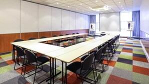 A conference room with a long table, chairs, a projector screen, and a presentation on it. - ibis Styles Nancy Sud (Houdemont)