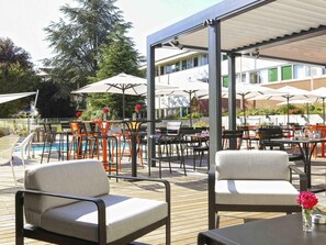 An outdoor seating area with tables and chairs, a pool, and umbrellas.
