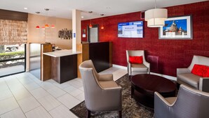A hotel lobby with a reception desk, seating area, and a large screen displaying information. - Best Western Murfreesboro (Murfreesboro)