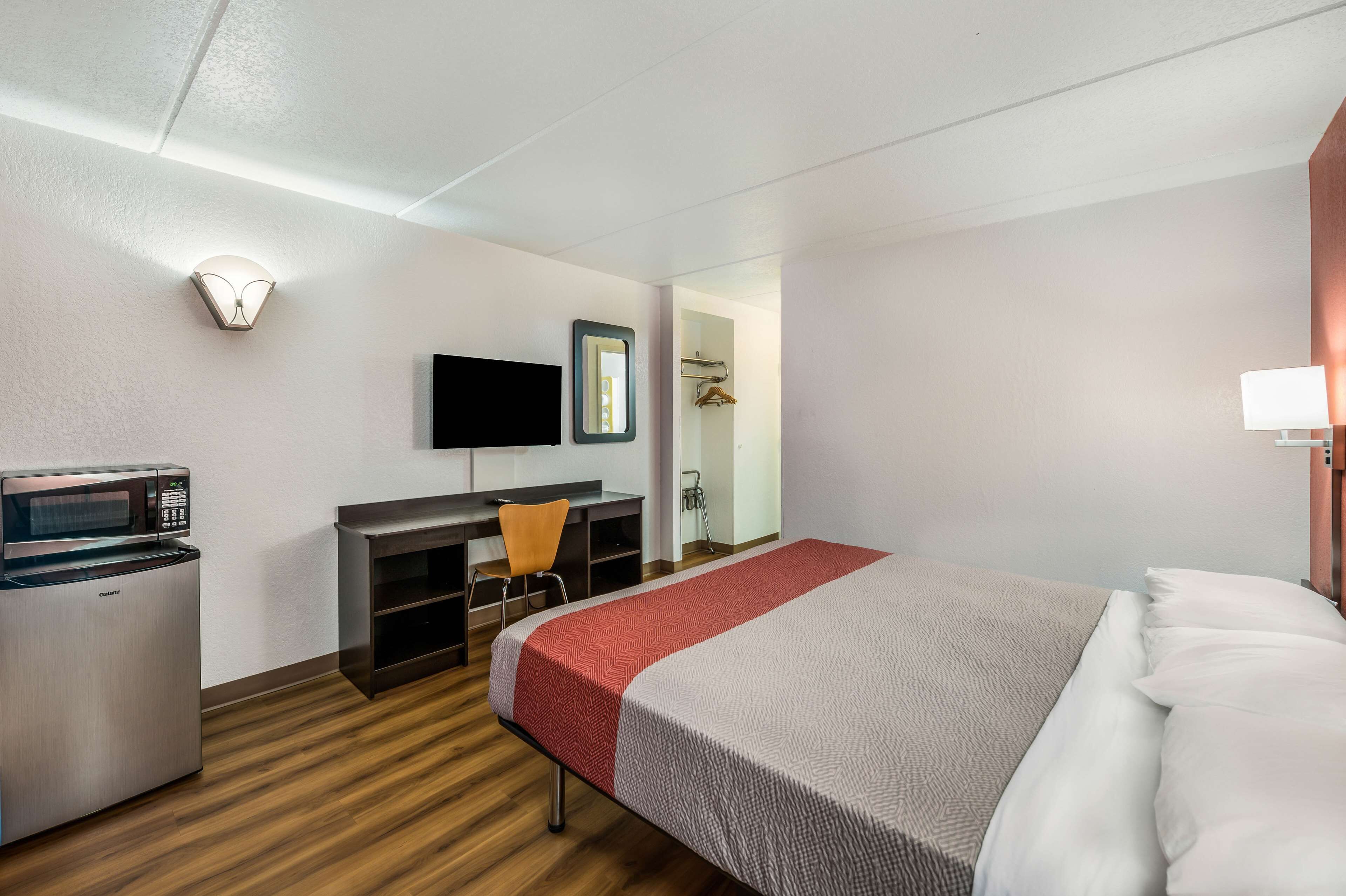 Une chambre d’hôtel comprenant un lit, un bureau avec une chaise, un four à micro-ondes, une télévision et un miroir.
