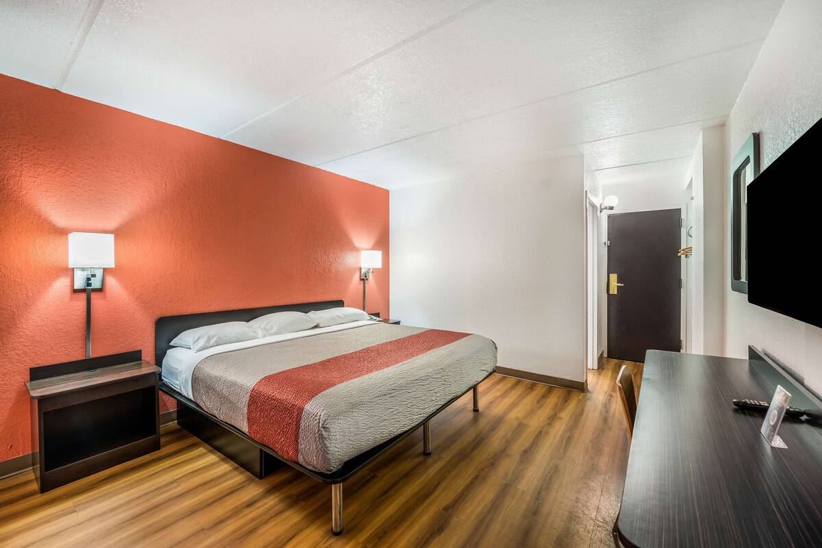 Une chambre d’hôtel avec un lit, des tables de chevet, un bureau et une télévision.