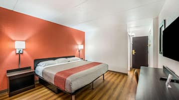 A hotel room with a bed, bedside tables, a desk, and a TV.