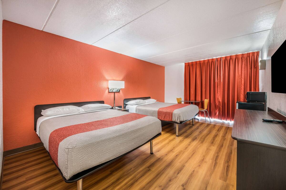 Une chambre d’hôtel avec deux lits, un bureau, une chaise et un téléviseur.