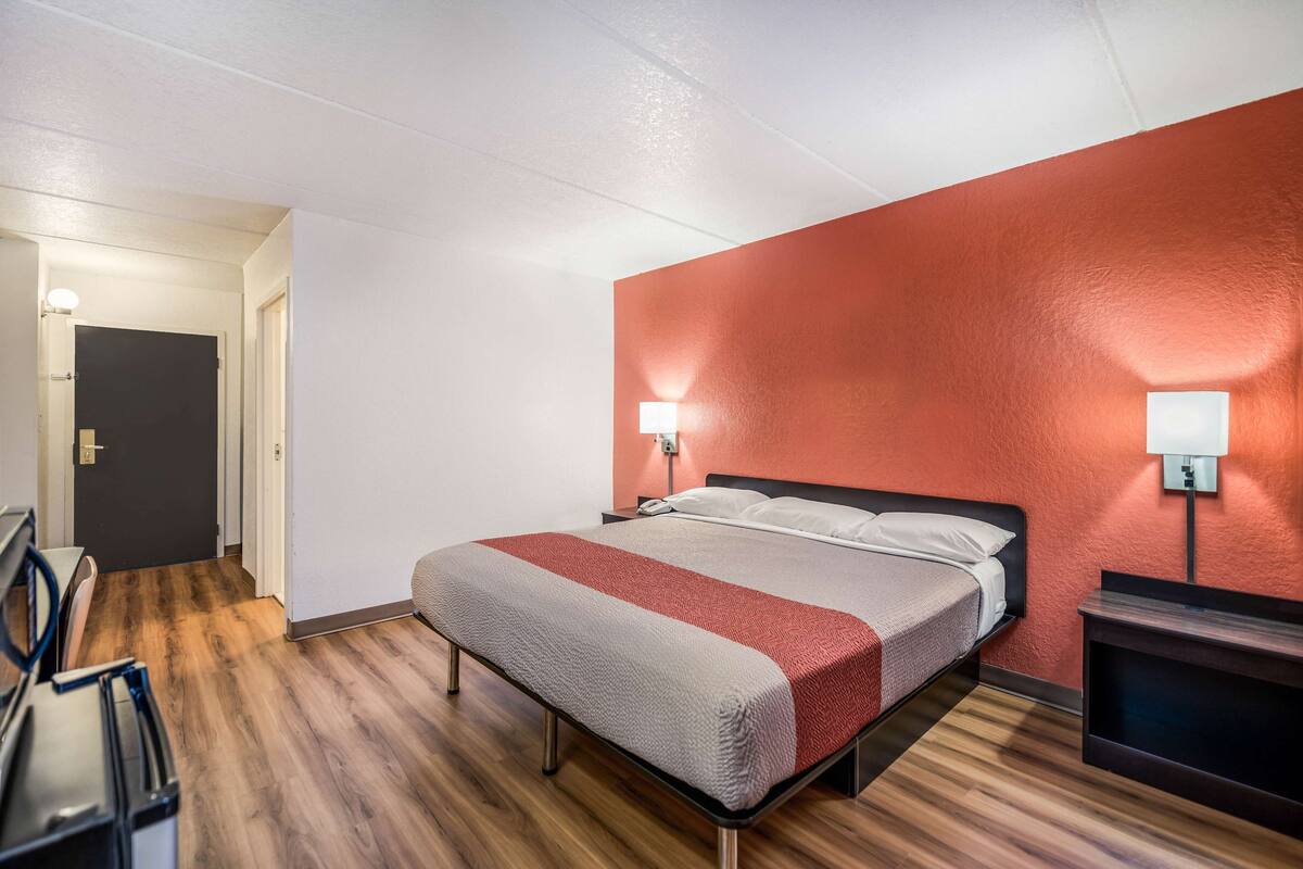 Une chambre d’hôtel avec un lit, des lampes de chevet, un bureau et une chaise.