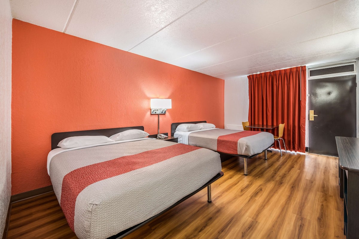 Une chambre d’hôtel avec deux lits, un bureau, une chaise et une porte.
