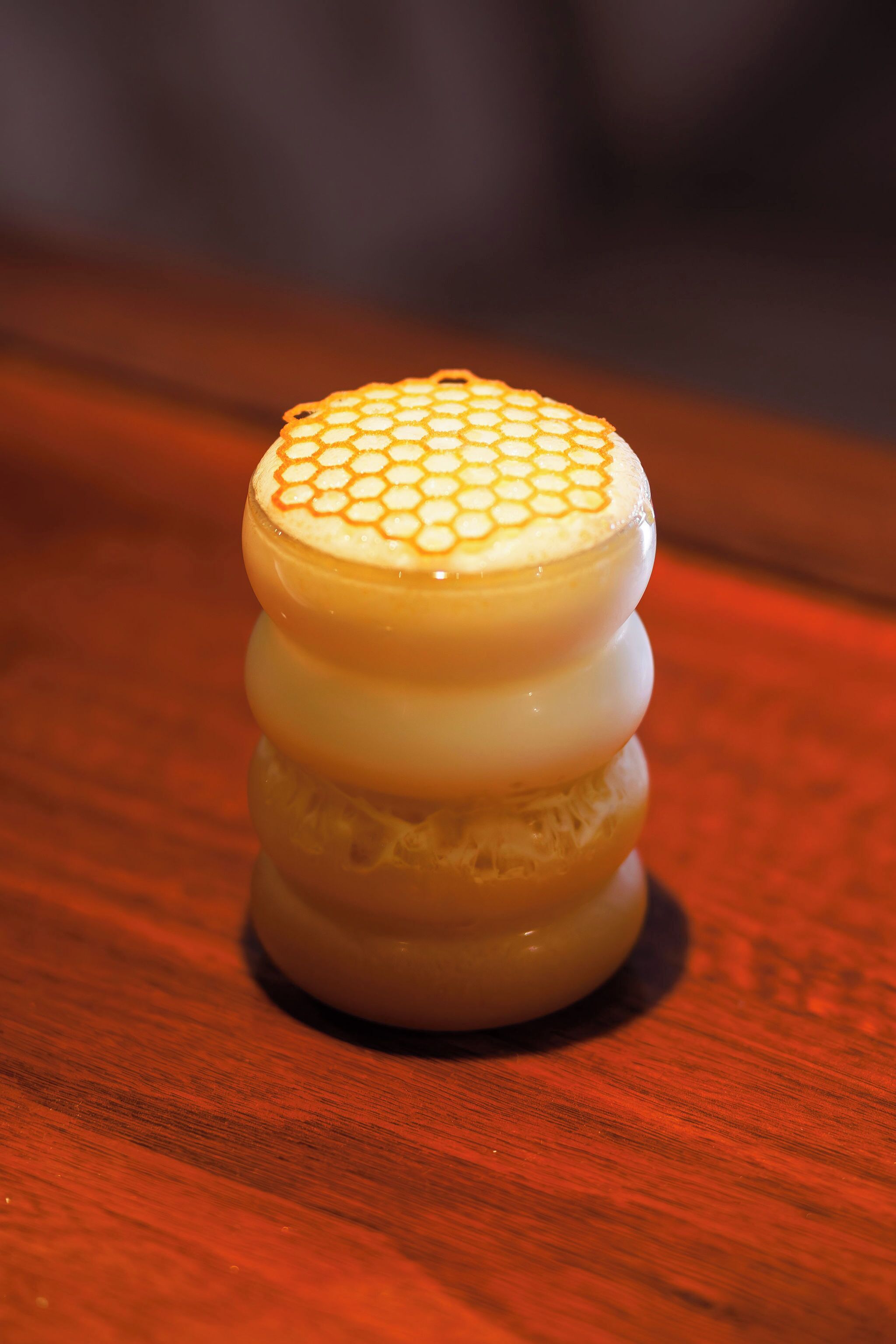 A stack of three cylindrical objects with a honeycomb pattern on top, placed on a wooden surface.
