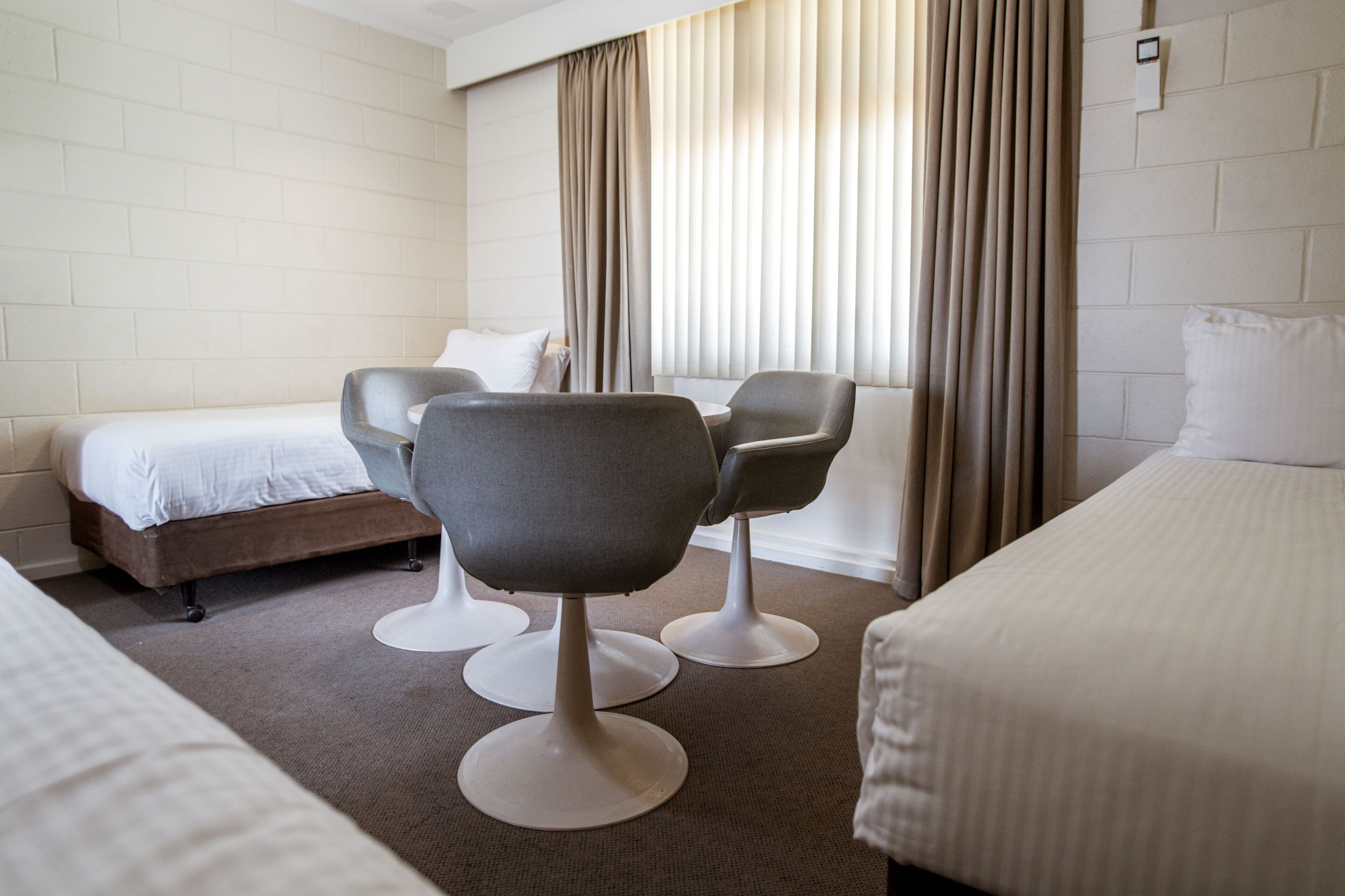 Una habitación de hotel con una cama, dos sillones, un sofá y una ventana con cortinas.