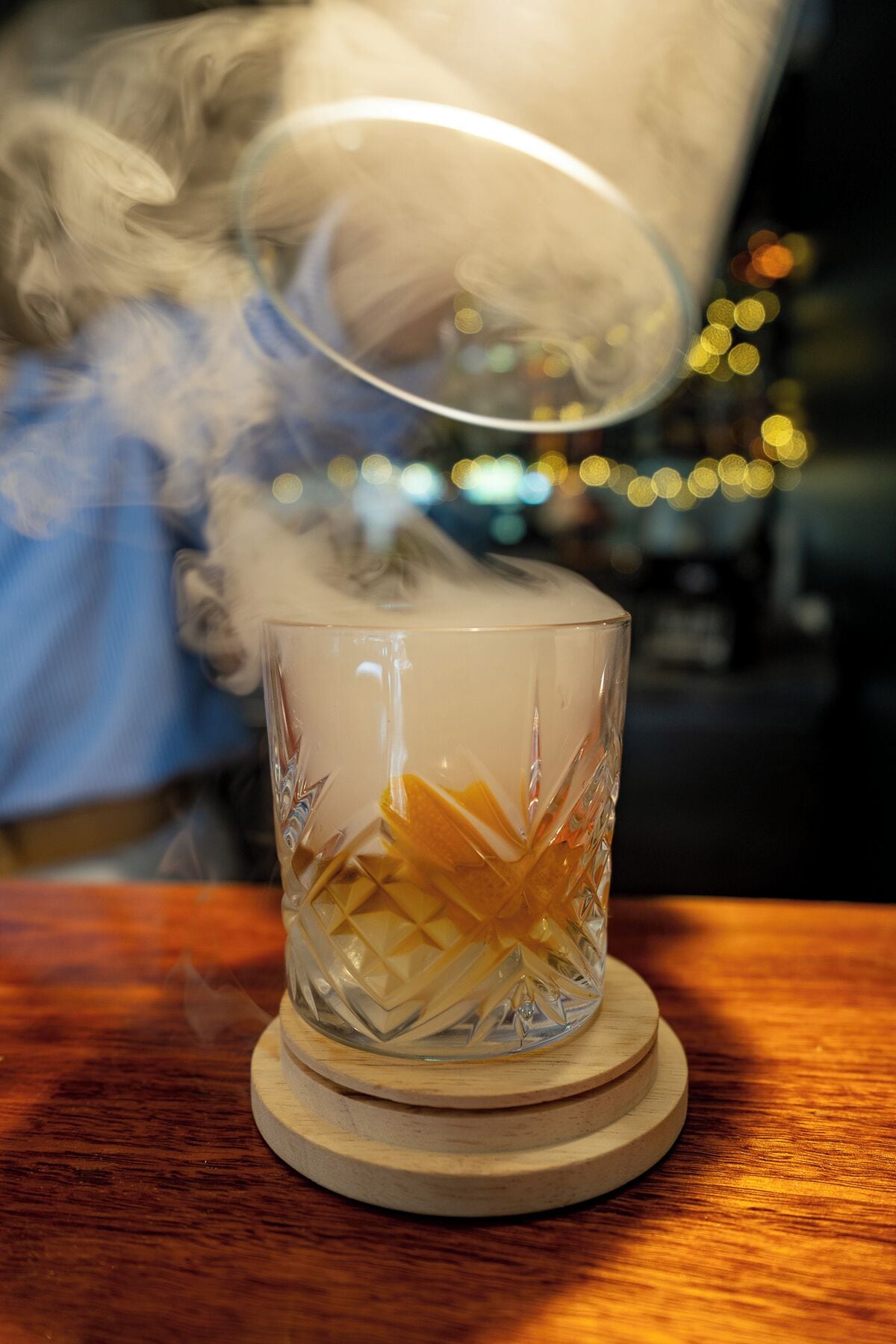 A clear glass with a geometric pattern on a wooden coaster.