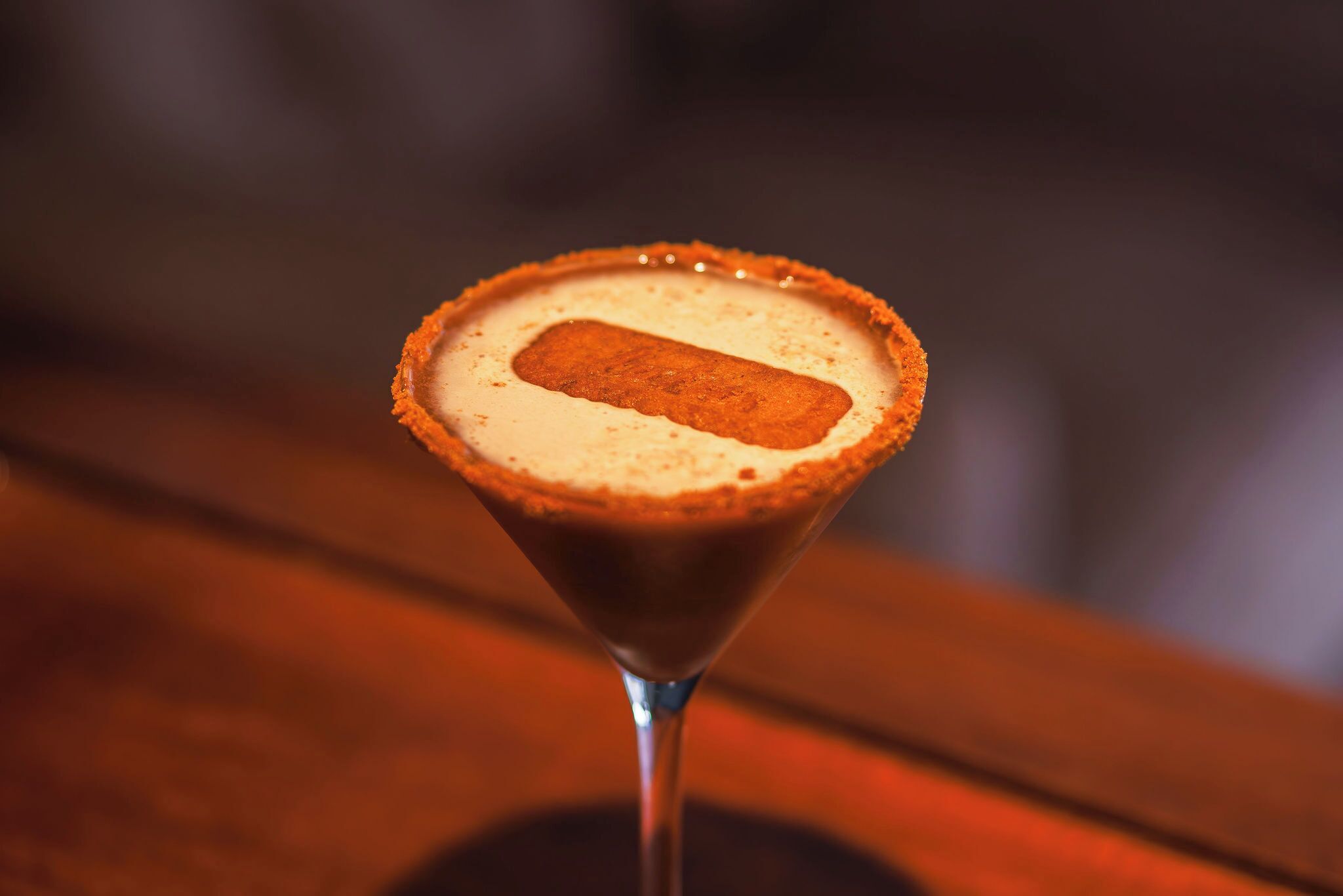 Un verre à martini surmonté d’une mousse crémeuse et dont le bord est décoré d’une couleur rappelant celle du chocolat.