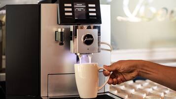 Une machine à café verse du café dans une tasse blanche.