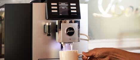 Eine Kaffeemaschine füllt Kaffee in eine weiße Tasse.