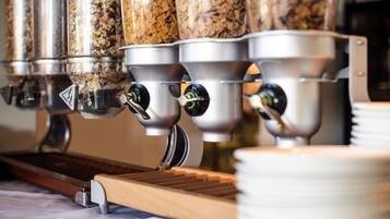 A coffee machine with multiple dispensers, a wooden tray, and stacked plates.