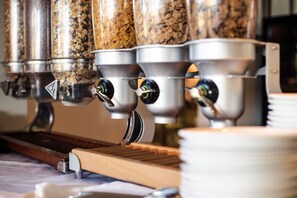 A coffee machine with multiple dispensers, a wooden tray, and stacked plates. - Hospitality Geraldton, SureStay Collection by Best Western (Geraldton)