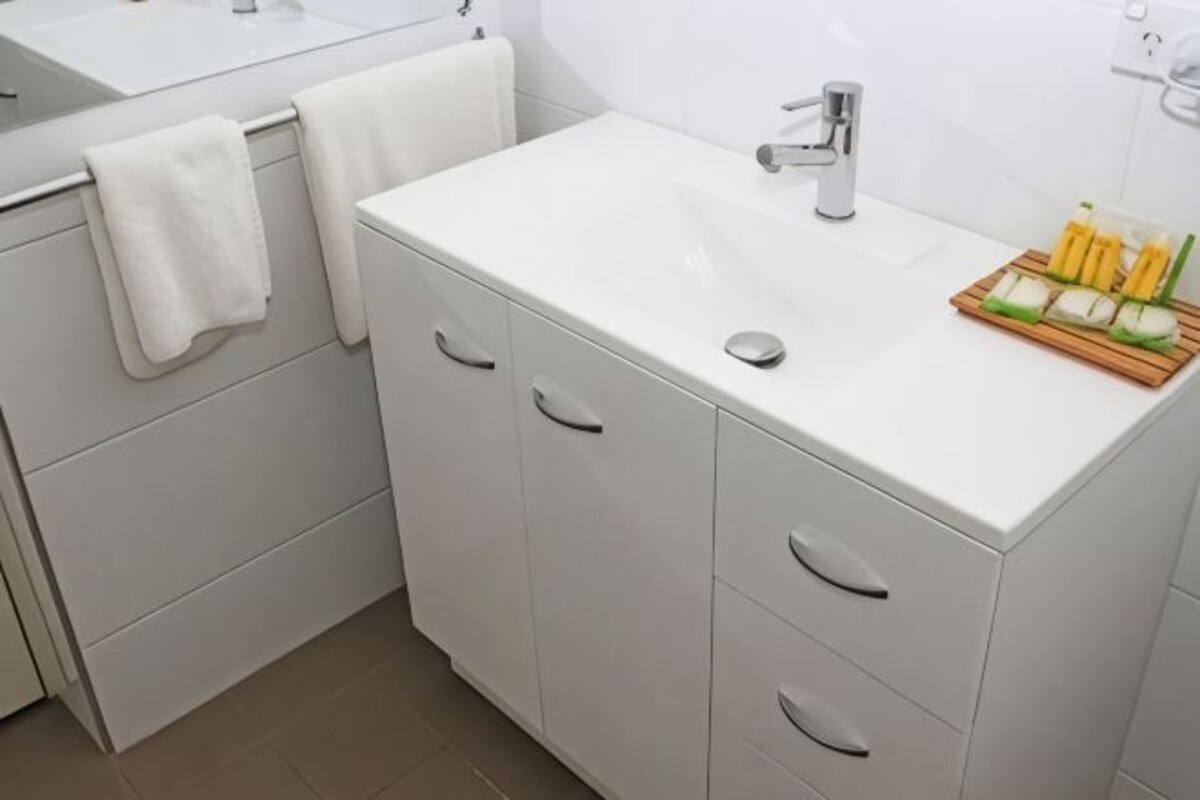 Een witte badkamer met een wastafel, spiegel en handdoekrek.