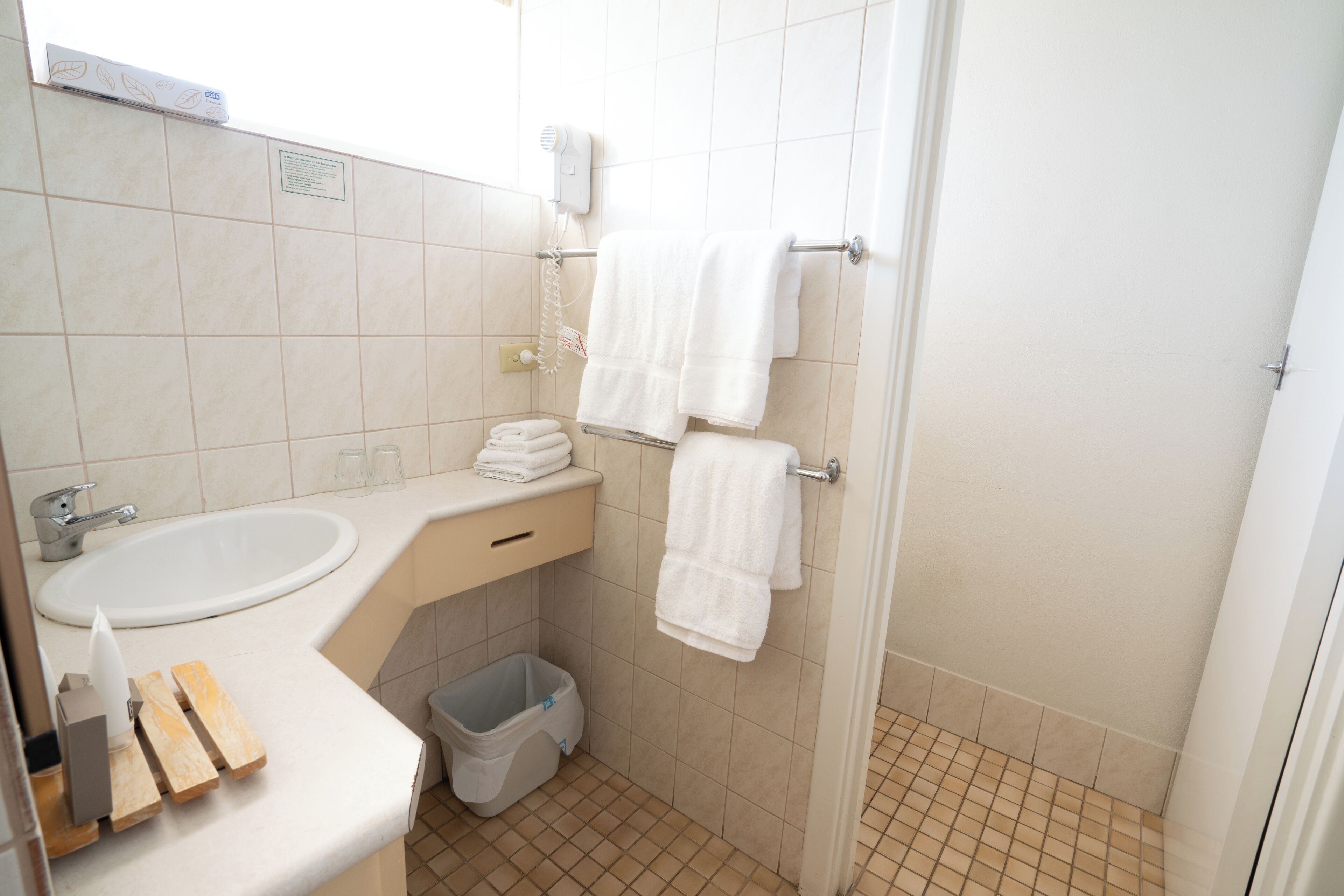 A small bathroom with a sink, towel rack, and a trash bin.