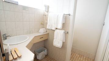 A small bathroom with a sink, towel rack, and a trash bin.