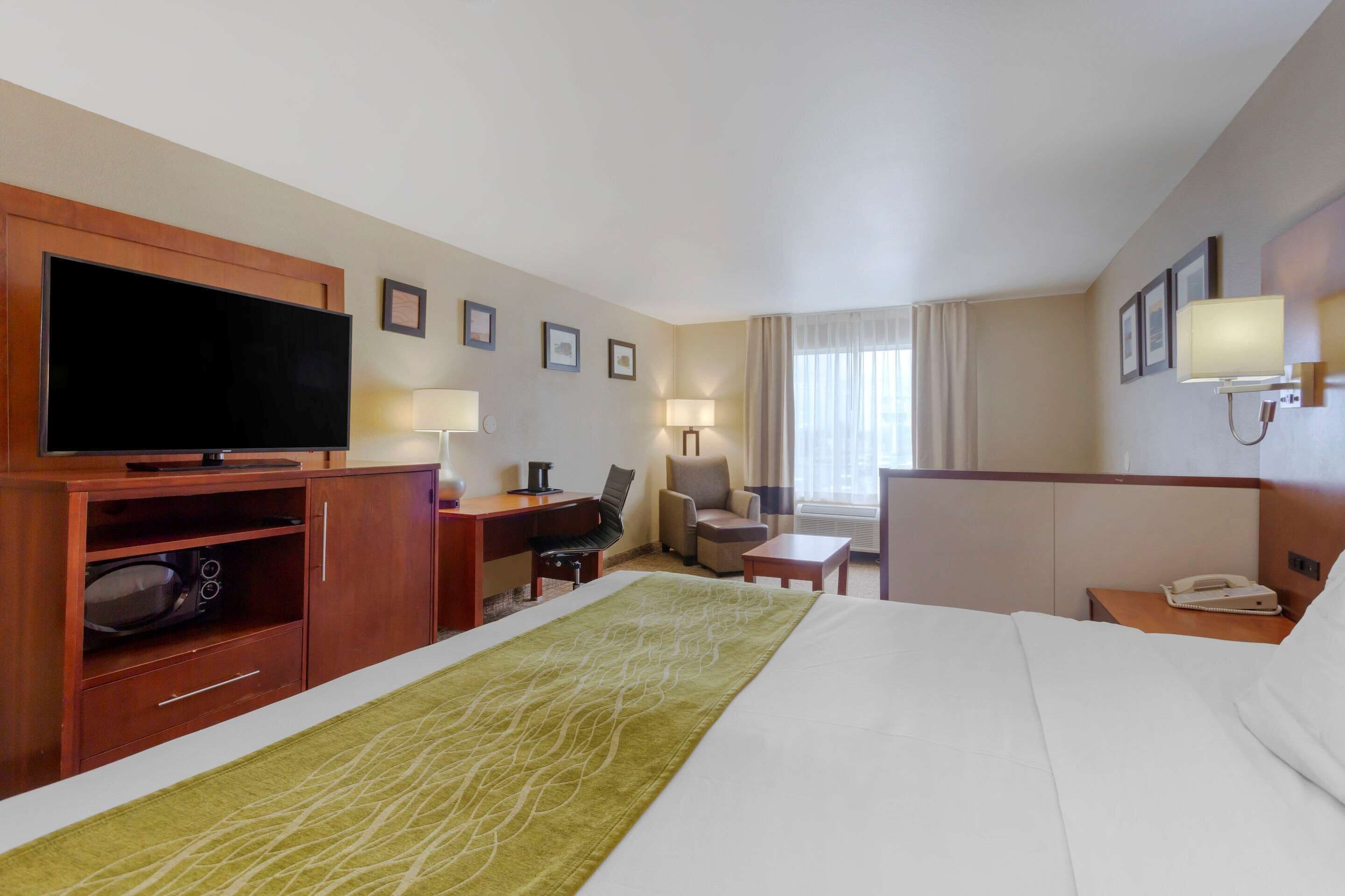Une chambre d’hôtel équipée d’un lit, d’un bureau, d’une télévision, d’une chaise, d’une lampe et d’un téléphone.
