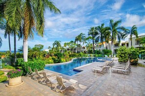 A resort pool area with lounge chairs, palm trees, and a view of the ocean. - Palms at Wailea Maui (Kihei)