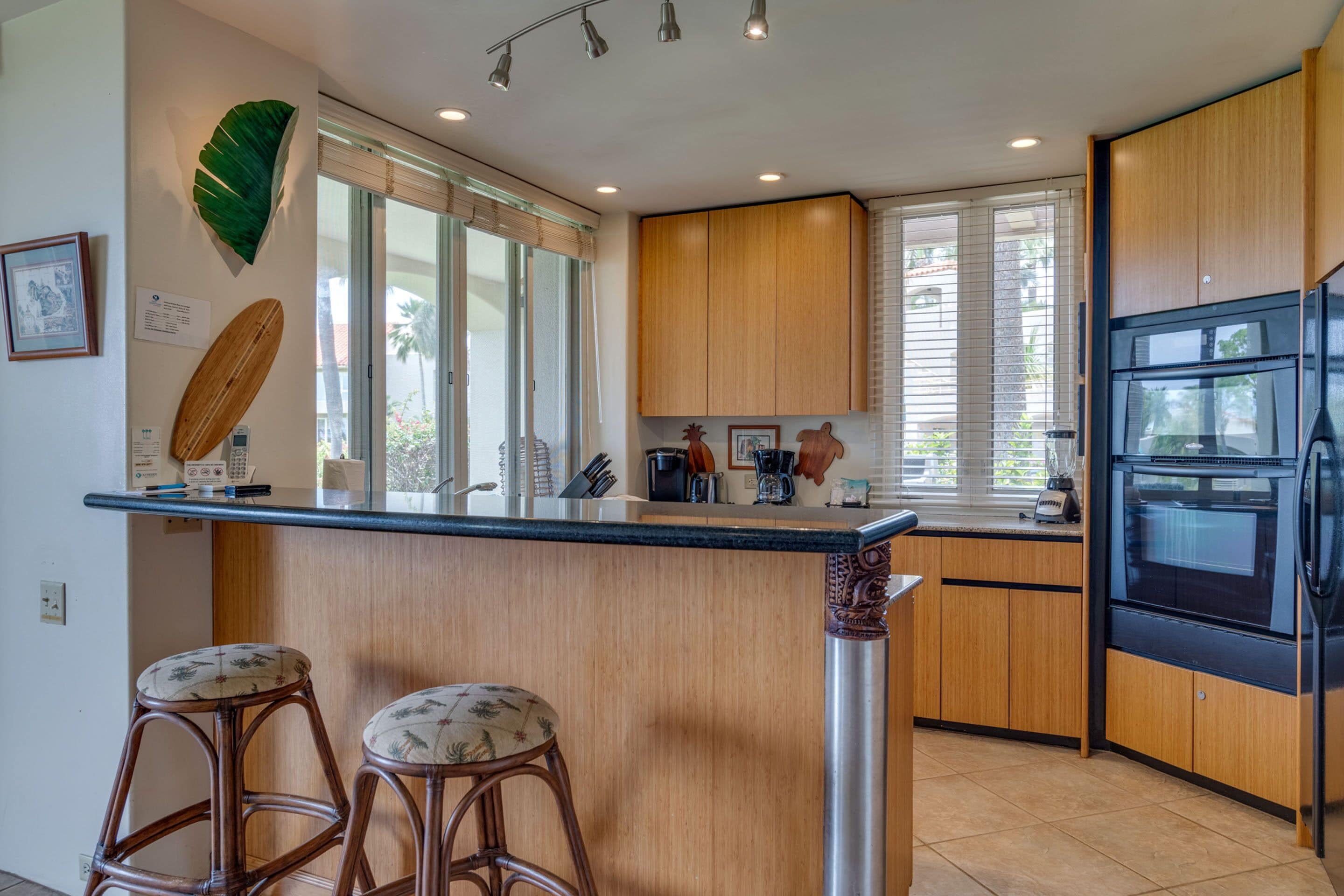 Una cocina moderna con armarios de madera, un refrigerador negro y una barra con dos taburetes.