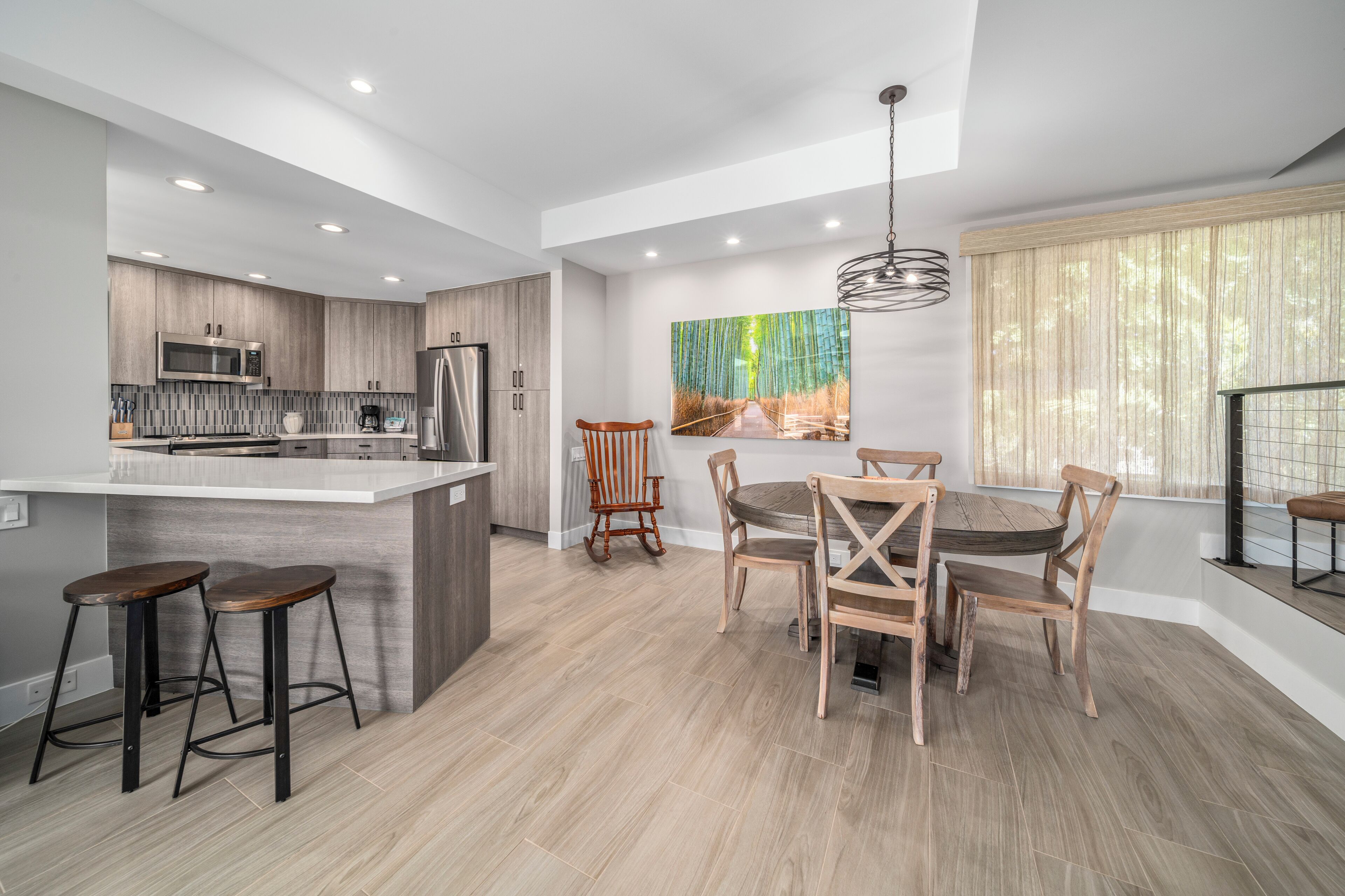 A modern kitchen with a central island, wooden chairs, and a dining table.