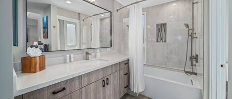 A modern bathroom with a large mirror, two sinks, a shower, and a wooden vanity.