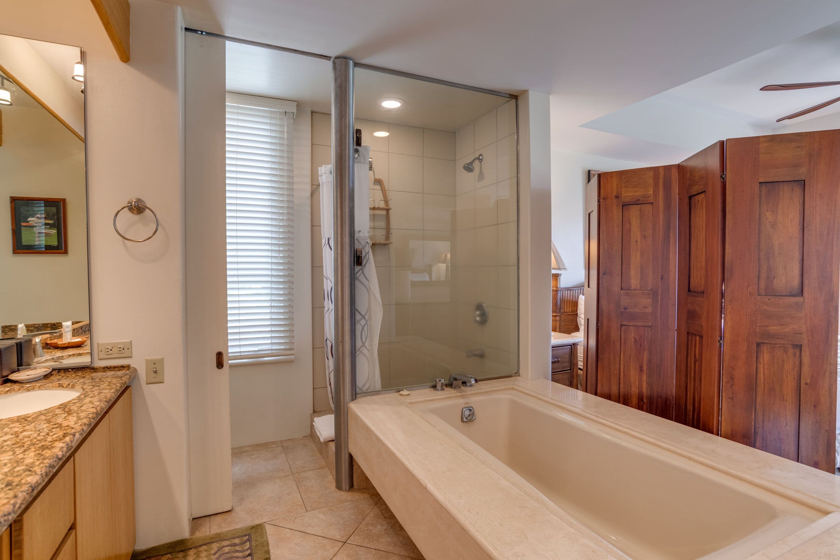 A modern bathroom with a large bathtub, a glass shower enclosure, wooden cabinets, and a vanity with a sink.