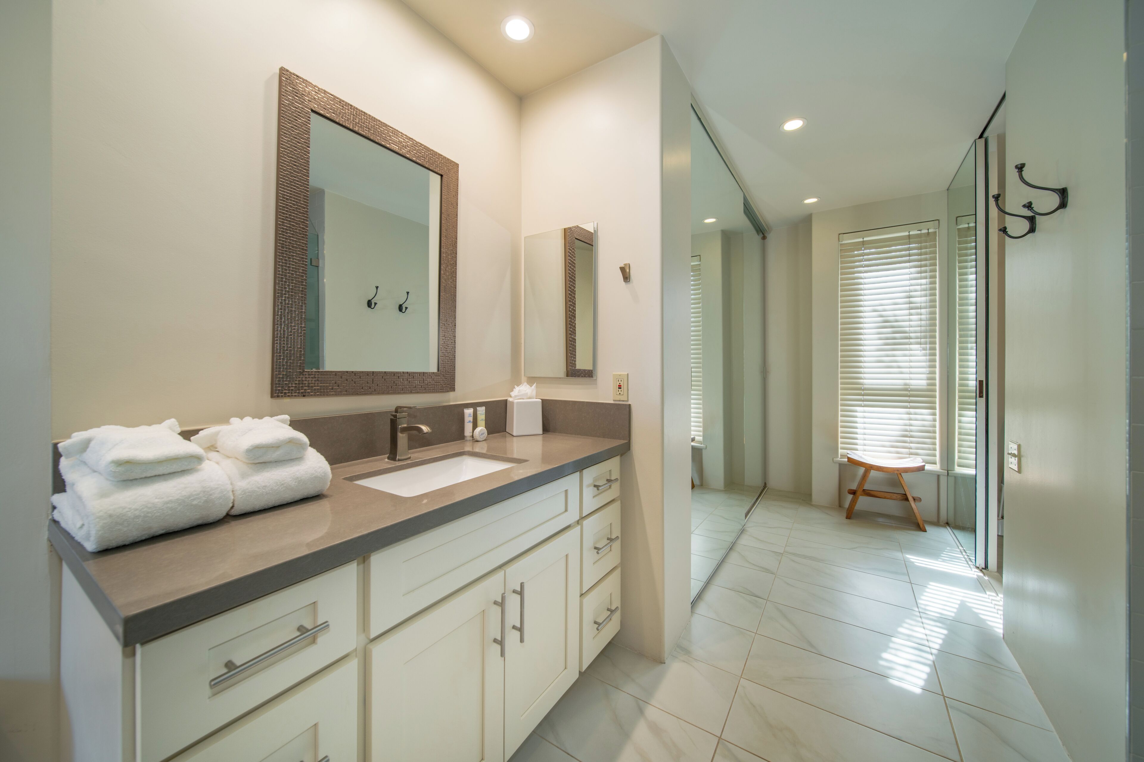 Un baño moderno con lavamanos doble, un espejo grande y un perchero para toallas.