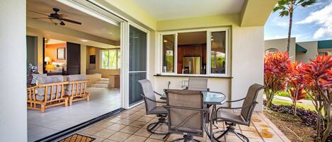 An open patio with a dining table and chairs, a ceiling fan, and a view of the interior living area.
