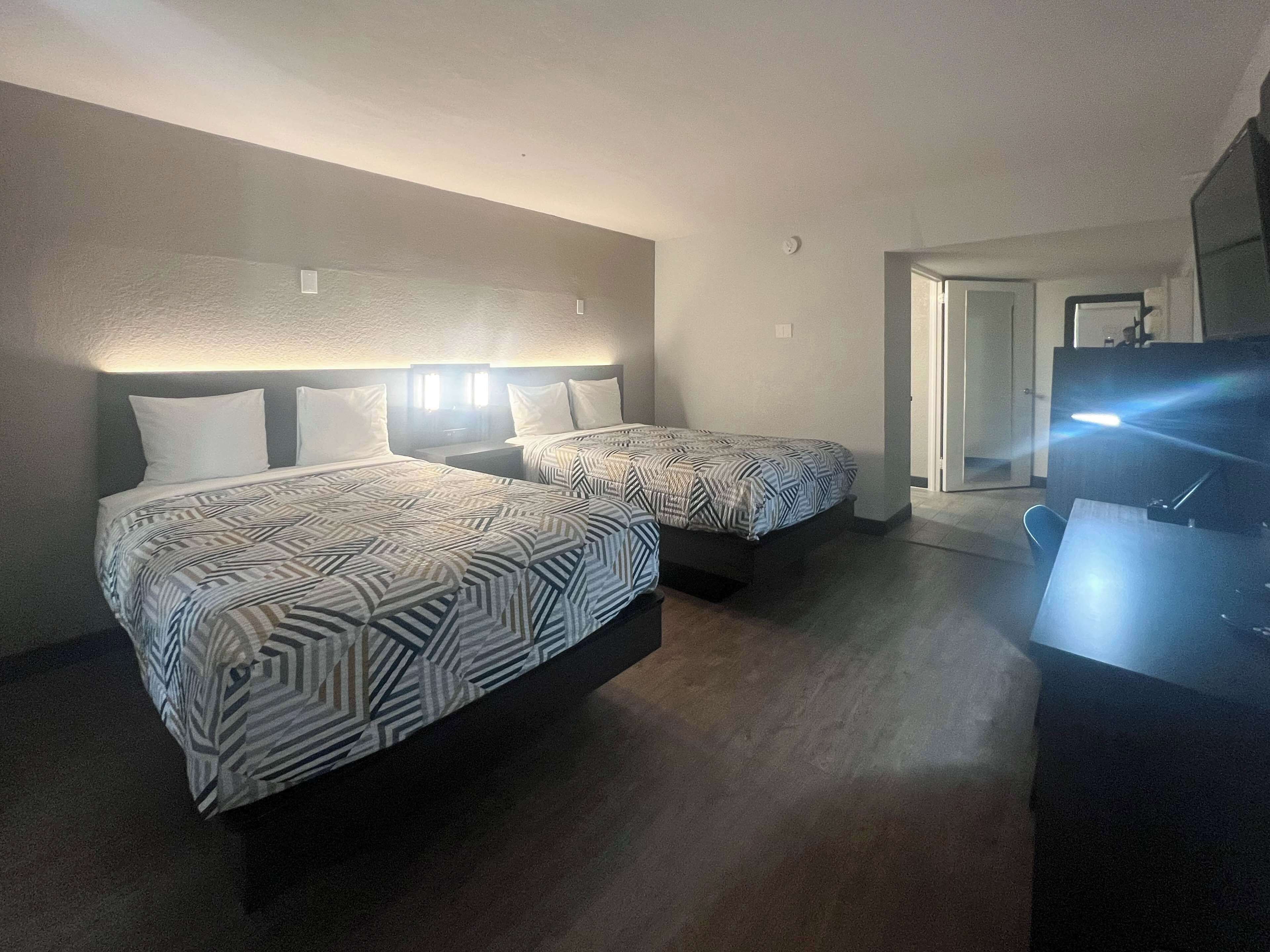 Habitación de hotel con dos camas, un escritorio y un televisor.