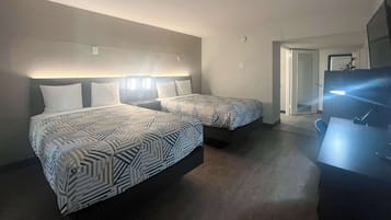 Habitación de hotel con dos camas, un escritorio y un televisor.