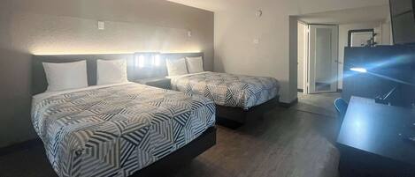 Habitación de hotel con dos camas, un escritorio y un televisor.