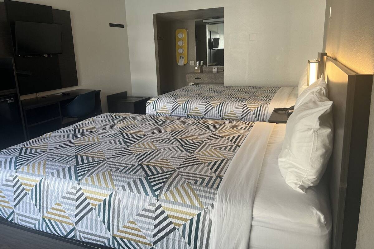 Hotellihuone, jossa on kaksi sänkyä, televisio ja työpöytä.