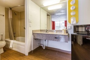 Un baño con ducha, inodoro, lavabo y microondas.