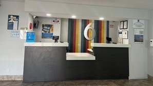 Un mostrador de recepción con un gran número 6 en la pared, una pantalla digital y varios carteles informativos.